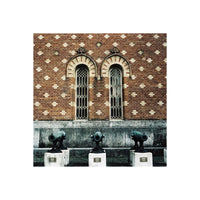 Three vintage cannons stand before a brick wall with arched windows, captured in LomoChrome Metropolis film's muted tones.