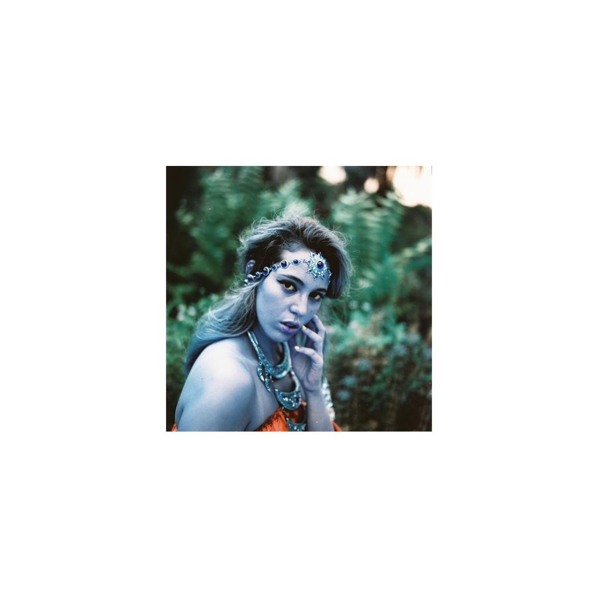 Portrait of a woman wearing a jeweled headpiece, captured with LomoChrome Turquoise film's signature cyan and gold tones.