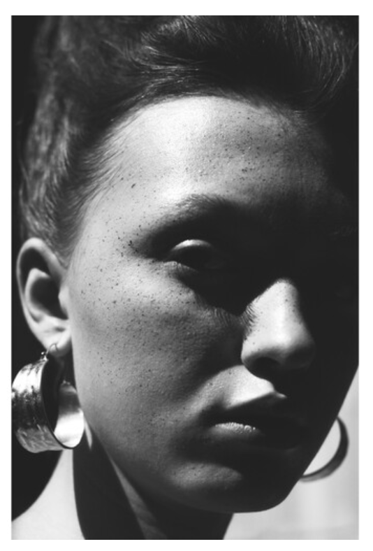 Black and white portrait up close of a woman with large hoop earrings.