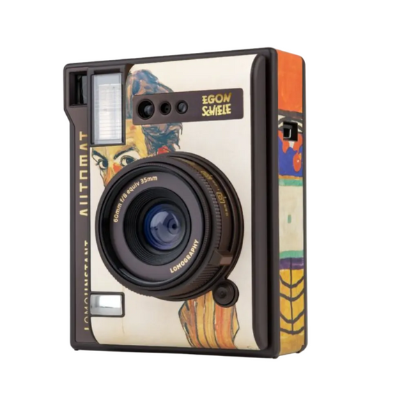 A retro-style instant camera featuring a cream-colored body with a colorful Art Nouveau illustration of a woman's face on the front. The camera has a black lens, black trim, and a side panel with orange, yellow, and blue geometric patterns.