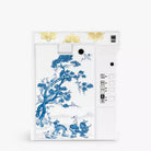 A white instant camera featuring a blue and white porcelain-style floral and bird illustration on the back panel, with gold decorative accents near the top and a white side control panel.