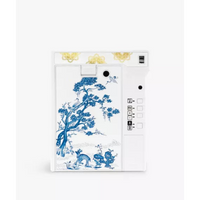 A white instant camera featuring a blue and white porcelain-style floral and bird illustration on the back panel, with gold decorative accents near the top and a white side control panel.