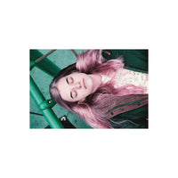 Person with pink-tinted hair lying on a green swing, captured with LomoChrome Purple 110 film's signature color shifts.
