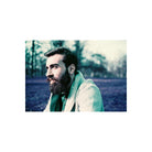 Bearded man in a textured green sweater captured with LomoChrome Purple 110 film, featuring surreal indigo and purple tones.