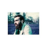 Bearded man in a textured green sweater captured with LomoChrome Purple 110 film, featuring surreal indigo and purple tones.