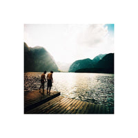 Two men standing on a wooden dock overlooking a lake and mountains, captured with vibrant Lomography 100 120 film.