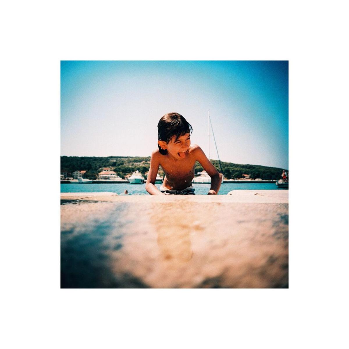 A young boy playing by the sea, captured with vibrant colors and sharp detail on Lomography 100 ISO 120 film.