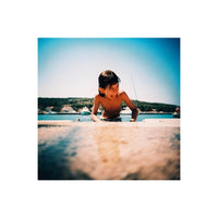 A young boy playing by the sea, captured with vibrant colors and sharp detail on Lomography 100 ISO 120 film.