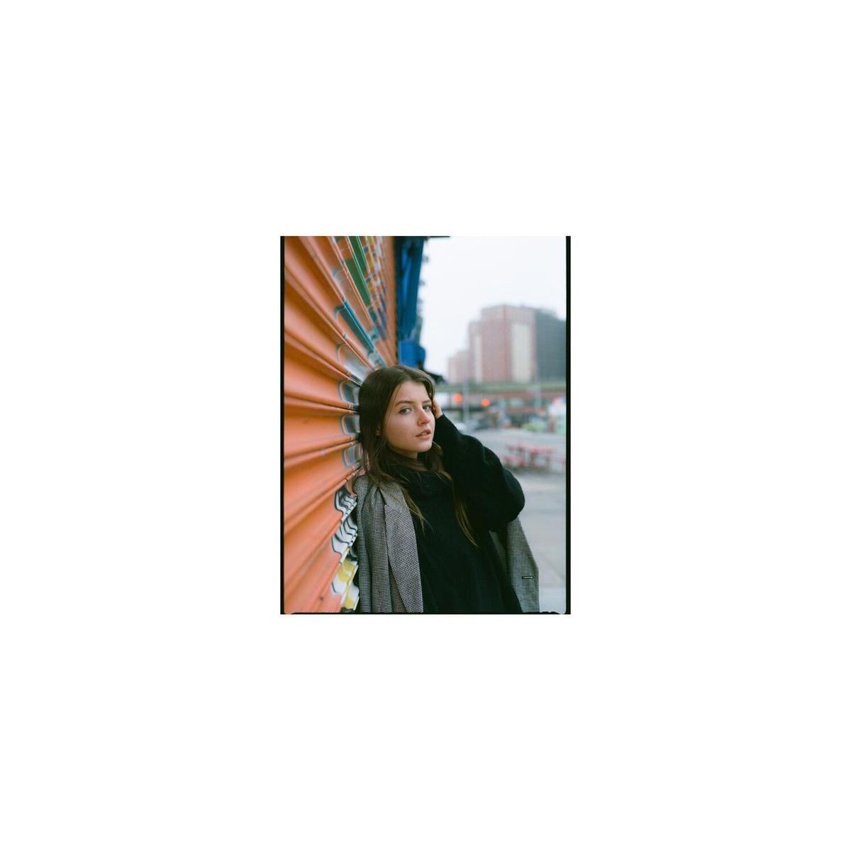 Portrait of a woman leaning against an orange corrugated wall, captured with vibrant Lomography 400 120 color film.