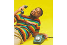 Man in a striped shirt holding a vintage rotary phone against a vibrant yellow background, captured on Lomography 400 film.