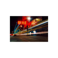 Nighttime city street with long-exposure light trails and vibrant red neon signage captured on 35mm film.