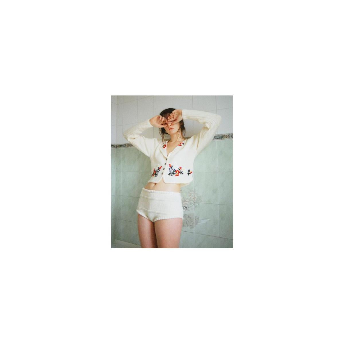 A person wearing a white floral cardigan and knit shorts, captured with the bold, grainy aesthetic of Lomography 800 film.