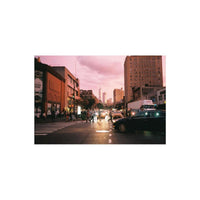 City street scene at dusk with pink sky, captured on 35mm film with bold colors and visible grain.