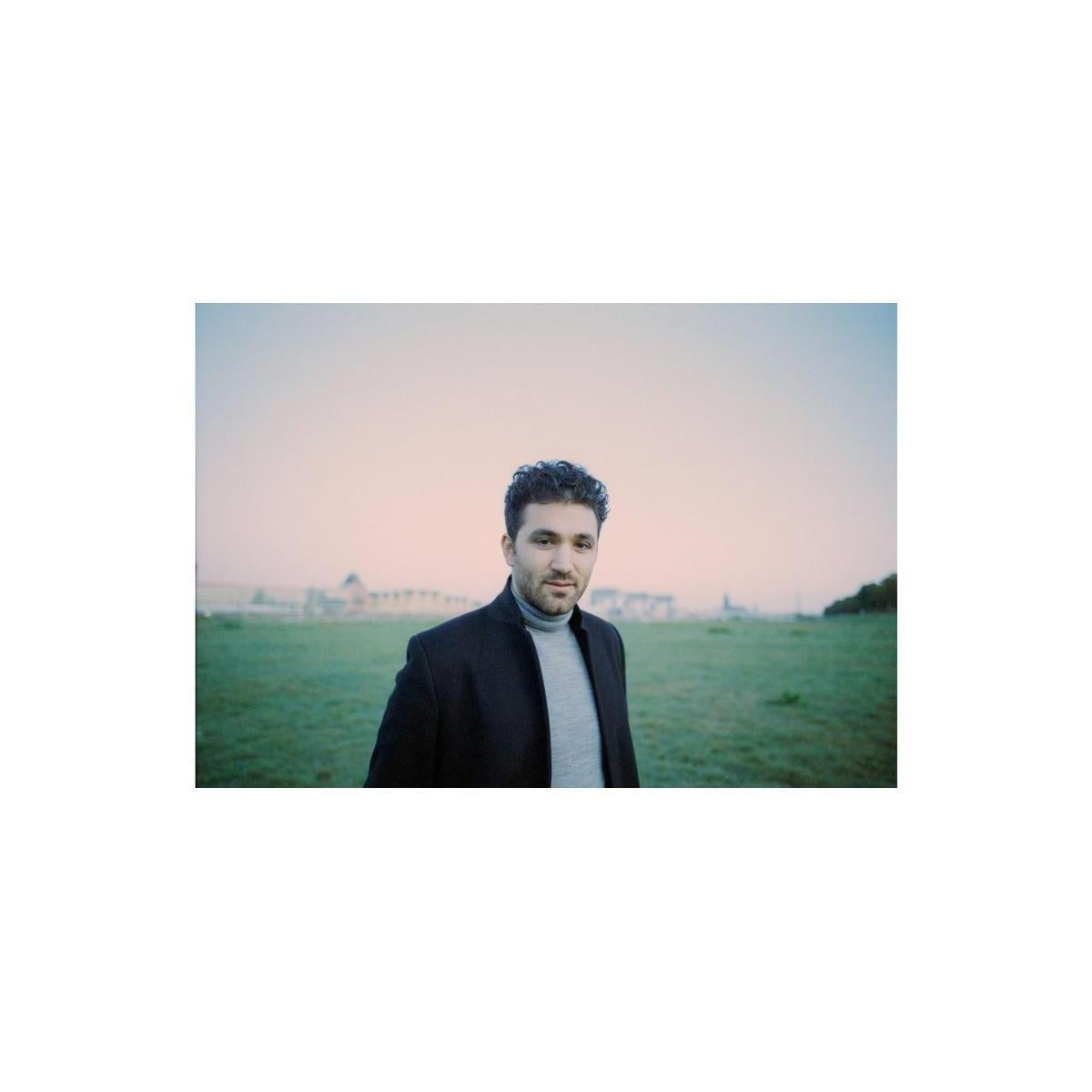 Portrait of a man in a black coat standing in a field at dusk, captured with Lomography 800 ISO 35mm color film.