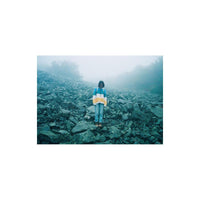 Person in a colorful sweater standing on a rocky, foggy hillside, captured with the grainy, saturated look of Lomography 800 film.