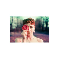 Person holding a red leaf over one eye, captured with vintage film tones and purple color shifts.