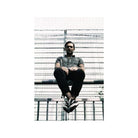 Man sitting on a metal fence, captured with high-contrast, muted tones typical of LomoChrome Metropolis 35mm film.