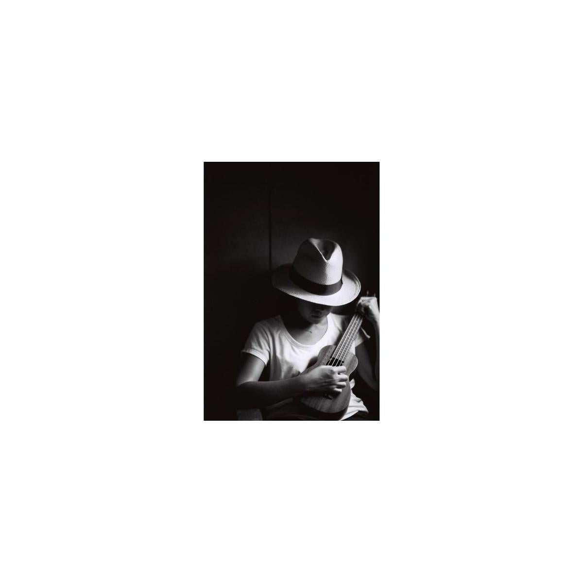 Black and white portrait of a person in a fedora playing a ukulele, captured with fine-grain Lomography Babylon Kino film.