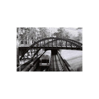 Black and white film sample showing a train passing under an arched bridge, captured with high-contrast 35mm film.