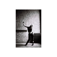High-contrast black and white portrait of a person posing against a brick wall, shot on Lomography Earl Grey 100 film.