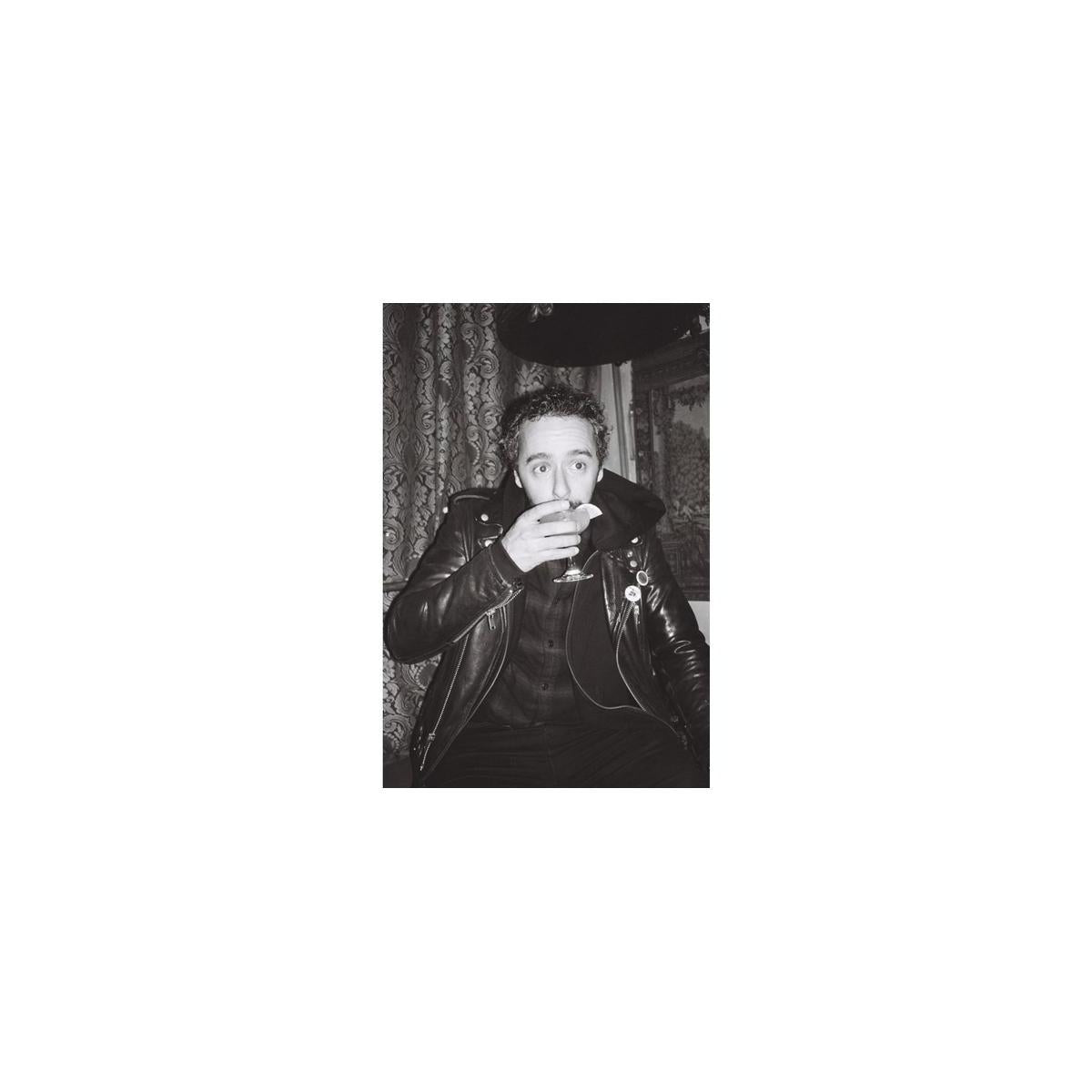 High-contrast black and white portrait of a man in a leather jacket holding a cocktail, shot on Lomography Earl Grey film.