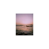 Surfer silhouetted against a sunset sky, captured with the muted, high-contrast aesthetic of Lomography Metropolis 35mm film.