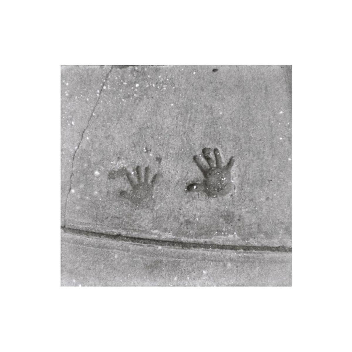 Black and white film shot of two handprints pressed into concrete, showing medium grain and sharp detail.