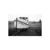Weathered wooden boat named Edith E resting in a field, captured in high-contrast black and white 35mm film style.