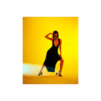 Woman in a black dress posing against a vibrant yellow background, captured with Lomography Redscale 120 film effects.
