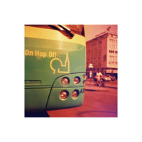 Green tour bus with Hop On Hop Off branding, captured with dramatic red and orange color shifts on 120 film.