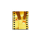 35mm film frame showing legs and sandals with a warm, experimental redscale color shift and high-contrast yellow tones.