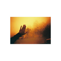 Hand reaching toward a rain-streaked window with warm, golden redscale film tones and high contrast.