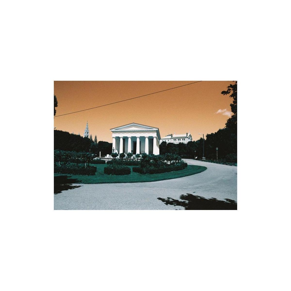 Neoclassical building in a park with turquoise foliage and a gold-toned sky, captured on LomoChrome Turquoise 35mm film.