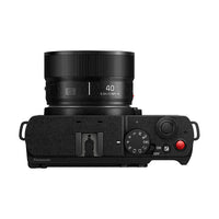 The top view of a black camera with a lens and a red button on a white background