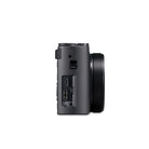 A black compact camera with an attached lens, shown from a side profile view against a solid white background.