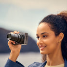 Woman holding a camera with a scenic background