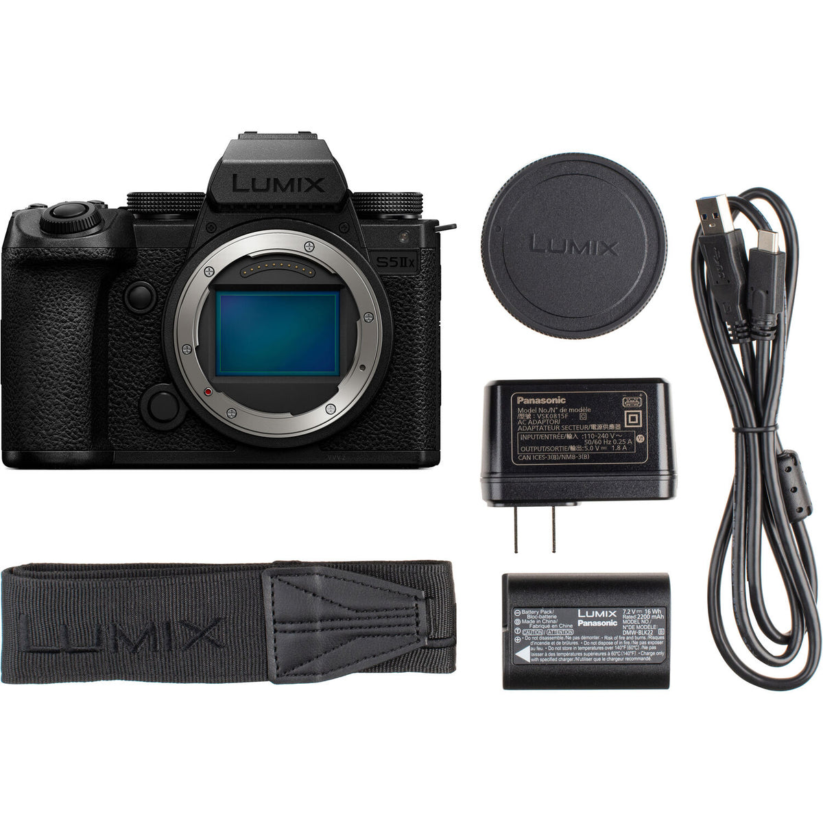 Panasonic Lumix camera with lens cap, battery, charger, and strap on a white background