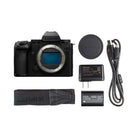 Panasonic Lumix camera with lens cap, battery, charger, and strap on a white background
