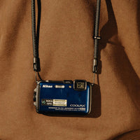 Nikon digital camera with strap on a brown background