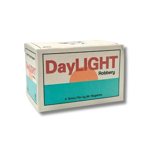 A boxed film package labeled DayLIGHT Robbery, shown on a plain white background. The box is off-white with a large teal band, red title text, black subtitle text, and a peach/orange sun graphic.