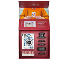 A boxed camera kit displayed open against a light gray background. The set includes a white and blue illustrated instant camera, several black lens attachments, a small red-and-white accessory card, and printed packaging inserts featuring a person in an orange sweater and product text.