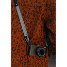 Camera with strap over a leopard print jacket