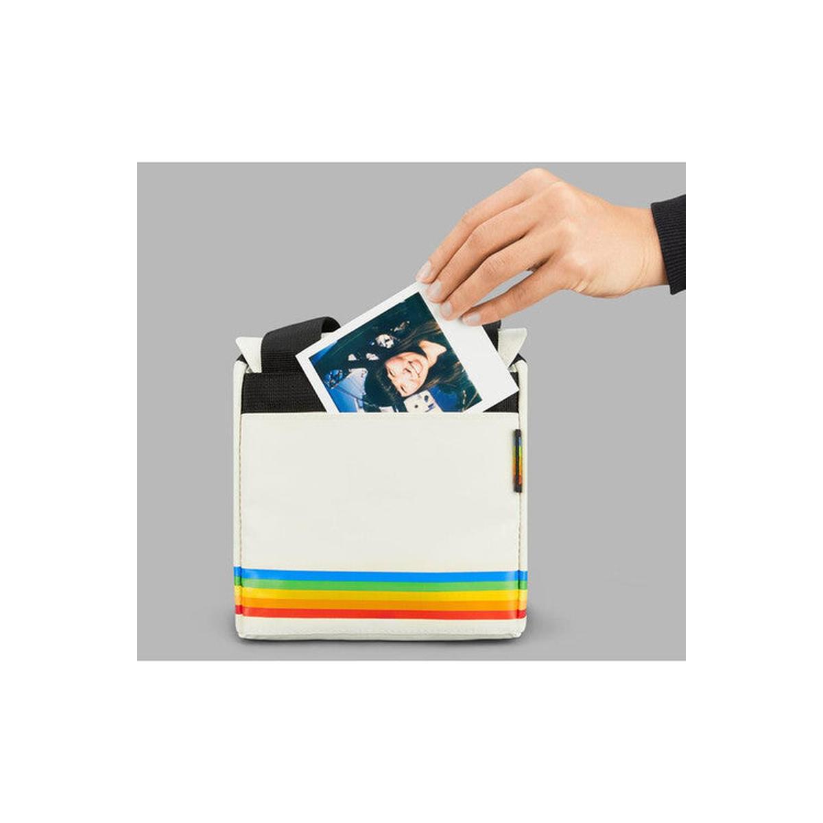 White Polaroid box camera bag made of soft nylon with a signature rainbow stripe and a hand inserting a photo print.