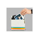 White Polaroid box camera bag made of soft nylon with a signature rainbow stripe and a hand inserting a photo print.