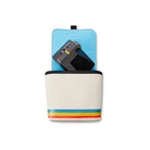 White nylon Polaroid box camera bag with a rainbow stripe, blue fleece interior, and a black camera inside.