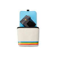 White nylon Polaroid box camera bag with a rainbow stripe, blue fleece interior, and a black camera inside.
