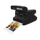 Matte black Polaroid instant camera ejecting a square film print with a portrait of a person holding yellow roses.