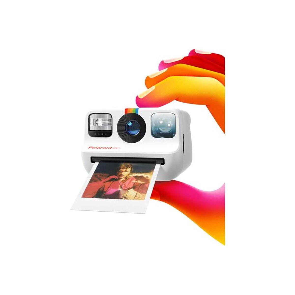 White Polaroid Go instant camera held by colorful hands, ejecting a small square color photo.
