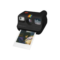 Compact black Polaroid Go instant camera with a red shutter button and a developing color photo print.