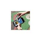 Hands holding a compact black Polaroid Go pocket photo album filled with small square instant photos.